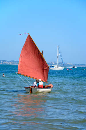 People sailing in a dinghy near the beach, Studland Bay, Dorset, England, UK, Western Europe.のeditorial素材