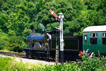 LSWR T9 Class 4-4-0 steam train at the railway station with the engine driver looking out of the cabin, Corfe, Dorset, England, UK, Western Europe.のeditorial素材