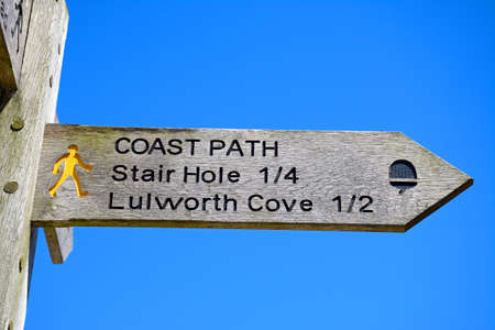 Wooden Lulworth Cove signpost against a blue sky, Lulworth Cove, Dorset, England, UK, Western Europe.の写真素材
