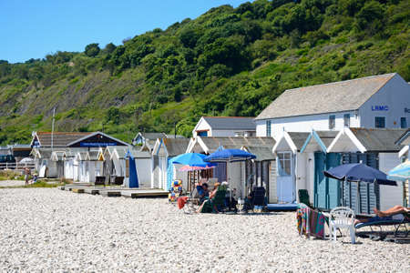 Holidaymakers relaxing outside beach huts on the pebbly beach, Lyme Regis, Dorset, England, UK, Western Europe.のeditorial素材