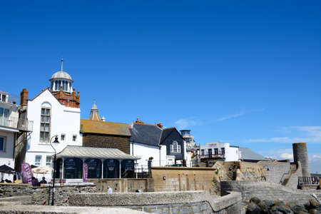 Seafront wall along Gun Cliff Walk with the Lyme Regis Museum and town buildings to the rear, Lyme...