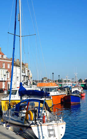 Yachts and fishing boats moored in the harbour with quayside buildings to the left, Weymouth, Dorset, England, UK, Western Europe.のeditorial素材