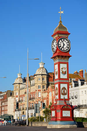 View of Queen Victorias Jubilee clock tower along the Esplanade promenade with hotels and guesthouses to the rear, Weymouth, Dorset, England, UK, Western Europe.のeditorial素材