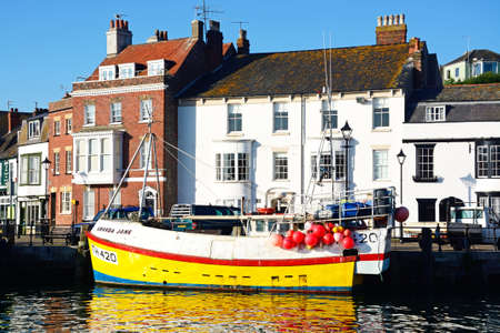 Fishing trawler moored in the harbour with quayside buildings to the rear, Weymouth, Dorset, England, UK, Western Europe.のeditorial素材