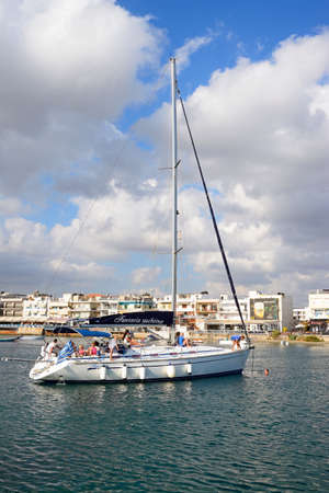 Tourists relaxing on a luxury yacht in the harbour with waterfront restaurants to the rear,...