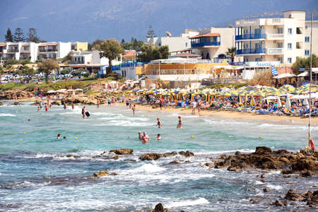 Tourists relaxing on the beach and in the sea with apartments and hotels to the rear, Stalida, Crete, Europe.のeditorial素材