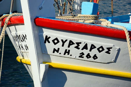Close up of a name painted on the front of a traditional wooden boat, Hersonissos, Crete, Europe.のeditorial素材