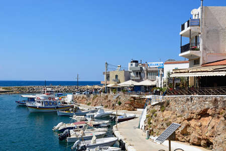 Boats moored in the harbour with waterfront restaurants to the right hand side, Sissi, Crete, Greece, Europe.のeditorial素材