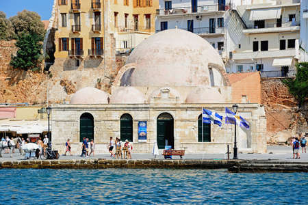 View of the Turkish mosque across the inner harbour with tourists passing by, Chania, Crete, Greece, Europe.のeditorial素材