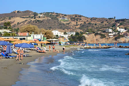 Tourists relaxing on Livadi Beach with restaurants to the rear, Bali, Crete, Greece, Europe.のeditorial素材
