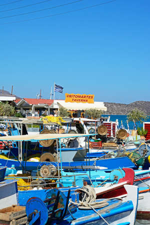 Traditional Greek fishing boats moored in the harbour with a taverna to the rear, Elounda, Crete, Greece, Europe.のeditorial素材