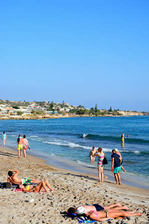 Tourists relaxing on the beach with views along the coastline, Hersonissos, Crete, Greece, Europe.のeditorial素材