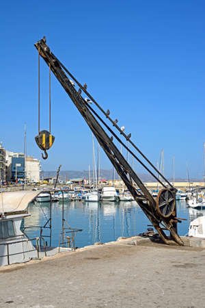 Dockside crane on the quayside with yachts and boats moored to the rear, Heraklion, Crete, Greece, Europe.のeditorial素材