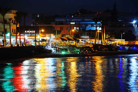 View of the beach and waterfront shops and restaurants at night, Hersonissos, Crete, Greece, Europe.のeditorial素材