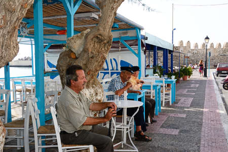 Three elderly Cretan men sitting at a pavement cafe by the harbour, Ierapetra, Crete, Greece, Europe.のeditorial素材