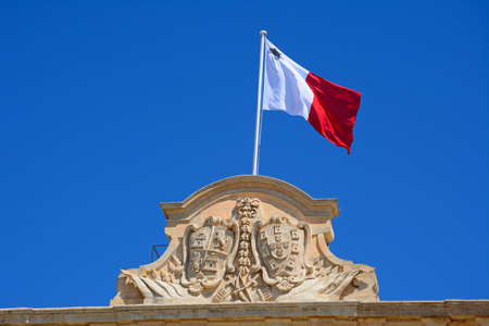 The coat of arms of Castille and Leon and Maltese flag on top of the Auberge de Castille (office of the Prime Minister) in Castille Square, Valletta, Malta, Europe.の写真素材