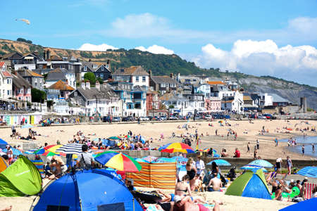 Holidaymakers relaxing on the sandy beach with the promenade to the rear, Lyme Regis, Dorset, England, UK, Western Europe.のeditorial素材