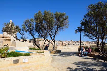 People relaxing in the Gardjola Gardens with views towards Valletta, Senglea, Malta, Europe.のeditorial素材
