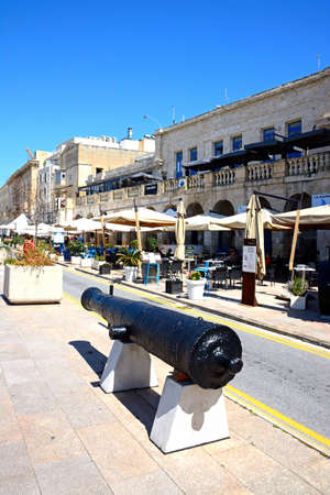 Cannon along the waterfront with pavement cafes to the rear, Vittoriosa (Birgu), Malta, Europe.のeditorial素材