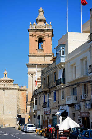 View along the waterfront shops towards St Lawrence church tower, Vittoriosa (Birgu), Malta, Europe.のeditorial素材