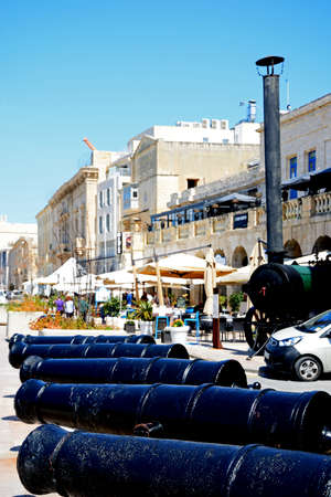 Row of Cannons along the waterfront with pavement cafes to the rear, Vittoriosa (Birgu), Malta, Europe.のeditorial素材