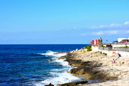 Tourists relaxing on the rocky shoreline, Bugibba, Malta, Europe.のeditorial素材