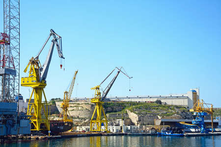 Industrial cranes in the docks with buildings to the rear, Paola, Malta, Europe.のeditorial素材