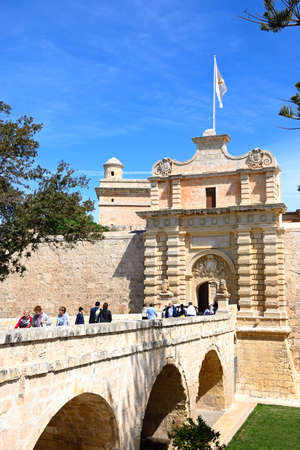 Tourists crossing the footbridge leading to the Town Gate and city centre, Mdina, Malta, Europe.のeditorial素材