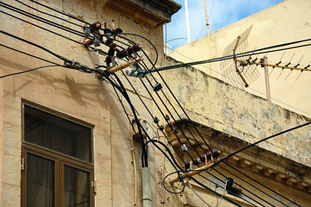 Electricity cables and a TV aerial on the front of a building, Bugibba, Malta, Europe.の写真素材