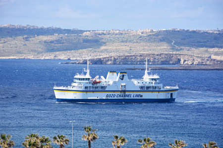 Gozo ferry in the bay with views towards Gozo and Comino, Paradise Bay, Malta, Europe.のeditorial素材