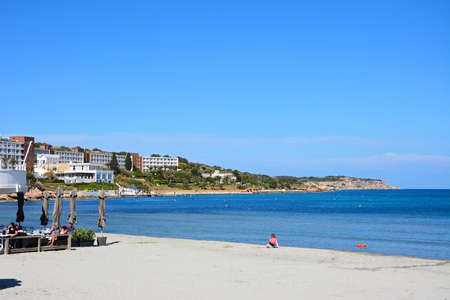 Tourists relaxing on the beach with the coastline to the rear, Mellieha, Malta, Europe.のeditorial素材