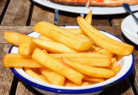 Crispy chunky chips in a metal dish on a wooden table within the citadel, Victoria (Rabat), Gozo,...