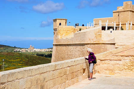 Tourists within the citadel looking at the view towards the Corpus Cristi church and countryside, Victoria (Rabat), Gozo, Malta, Europe.のeditorial素材