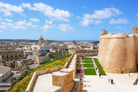 Fortified buildings and landscaped gardens of the old moat within the citadel with views towards the city and Corpus Cristi Parish Church, Victoria (Rabat), Gozo, Malta, Europe.のeditorial素材