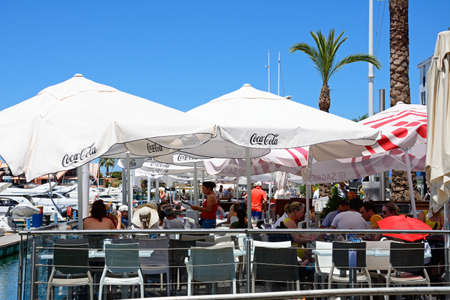 Tourists relaxing at a waterfront restaurant with yachts to the left hand side, Vilamoura, Algarve, Portugal, Europe.のeditorial素材
