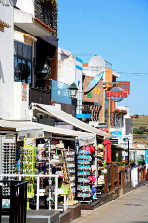 View along a village street with shops and restaurants leading towards the estuary, Alvor, Algarve, Portugal, Europe.のeditorial素材