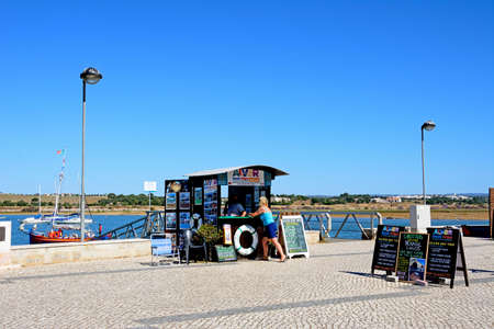 Boat trips booking office along the waterfront with views across the estuary, Alvor, Algarve,...