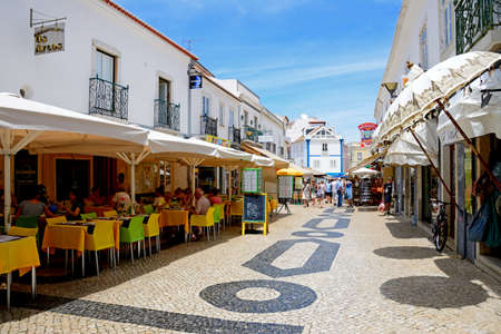 Tourists relaxing at pavement cafes along R 25 de Abril in the old town, Lagos, Algarve, Portugal,...