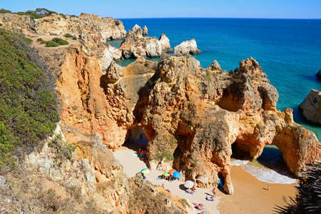 Elevated view of the cliffs with tourists relaxing on a secluded beach, Praia da Rocha, Portimao, Algarve, Portugal, Europe.のeditorial素材
