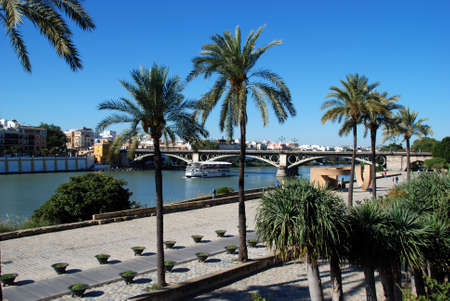 SEVILLE, SPAIN - NOVEMBER 15, 2008 - Pleasure boat on the Guadalquivir river with the Triana bridge to the rear, also known as the Isabel II bridge, Seville, Seville Province, Andalusia, Spain, Europe, November 15, 2008.のeditorial素材