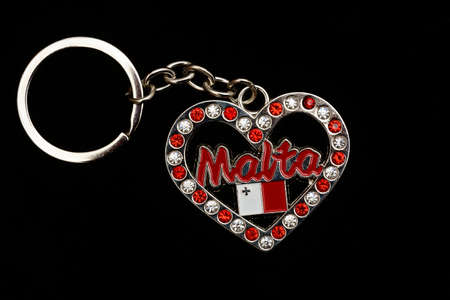 Ruby and diamond encrusted heart shaped Maltese key ring against a black background