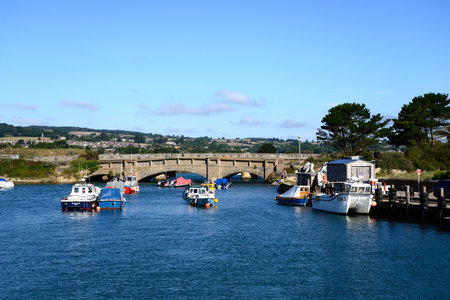 AXMOUTH, UK - AUGUST 30, 2022 - Bridge across the River Axe with small fishing boats in the foreground and the Devon countryside to the rear, Axmouth, Devon, UK, Europe, August 30, 2022.のeditorial素材