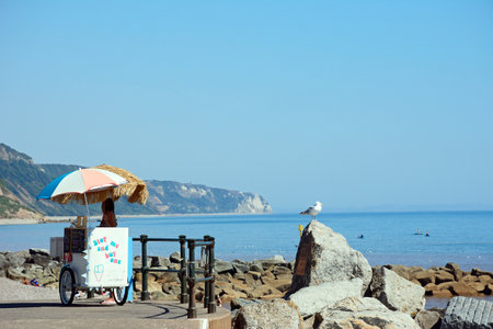SIDMOUTH, UK - AUGUST 11, 2022 - Ice cream seller on the promenade at the end of the beach with views along the coastline, Sidmouth, Devon, UK, Europe, August 11, 2022.のeditorial素材