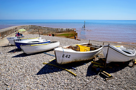 SIDMOUTH, UK - AUGUST 11, 2022 - Small fishing boats on the beach with views along the coastline, Sidmouth, Devon, UK, Europe, August 11, 2022.のeditorial素材