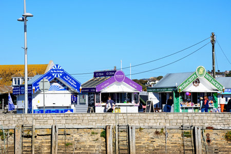 WEST BAY, UK - OCTOBER 10, 2022 - Tourists looking at snack kiosks alongside the harbour in the...
