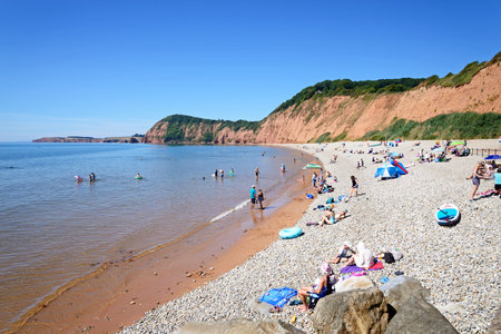 SIDMOUTH, UK - AUGUST 08, 2022 - Elevated view of tourists relaxing on Jacobs Ladder beach with cliffs to the rear, Sidmouth, Devon, UK, Europe, August 08, 2022.のeditorial素材