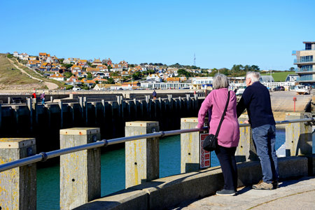 WEST BAY, UK - OCTOBER 10, 2022 - A couple looking across the harbour towards the town, West Bay, Dorset, UK, Europe, October, 2022.のeditorial素材