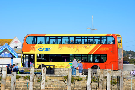 WEST BAY, UK - OCTOBER 10, 2022 - Tourists aboard a Jurassic Coaster bus in the harbour area, West Bay, Dorset, UK, Europe, October, 2022.のeditorial素材