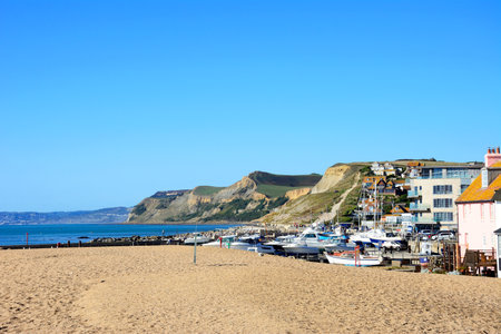WEST BAY, UK - OCTOBER 10, 2022 - View looking West towards the beach and cliffs with boats in dry dock in the foreground, West Bay, Dorset, UK, Europe, October, 2022.のeditorial素材