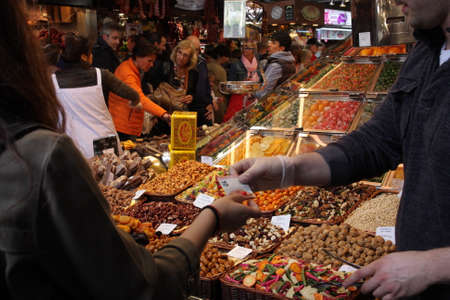 Dried fruit stand and customer at the market La Boqueria, Barcelona.
